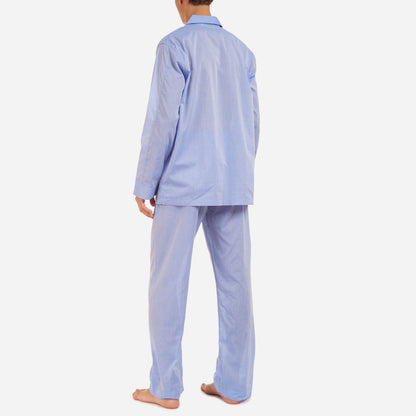 A back-facing model is wearing a long pajama set made of blue cotton batiste fabric.