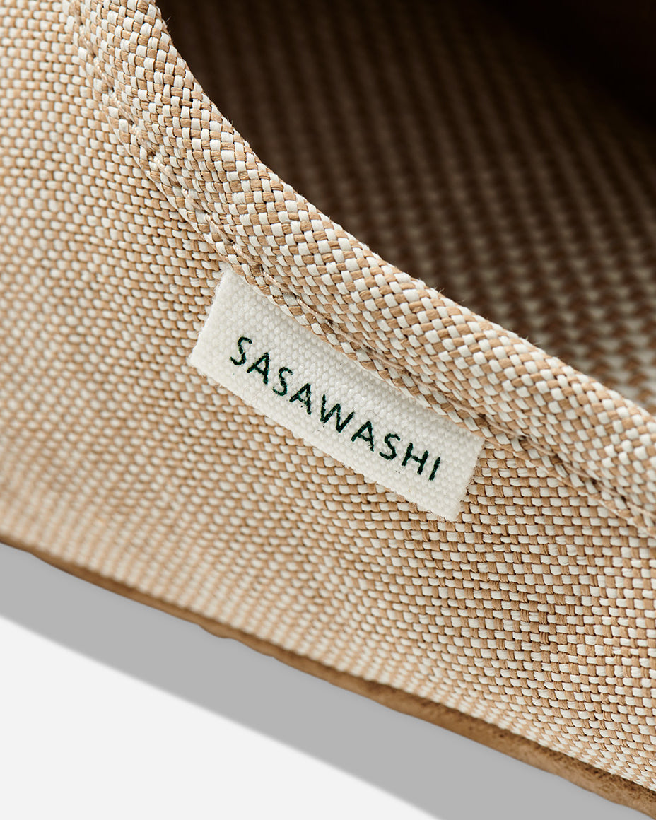 Up-close image of the side of a beige color slipper with Sasawashi written in black on a white tag.