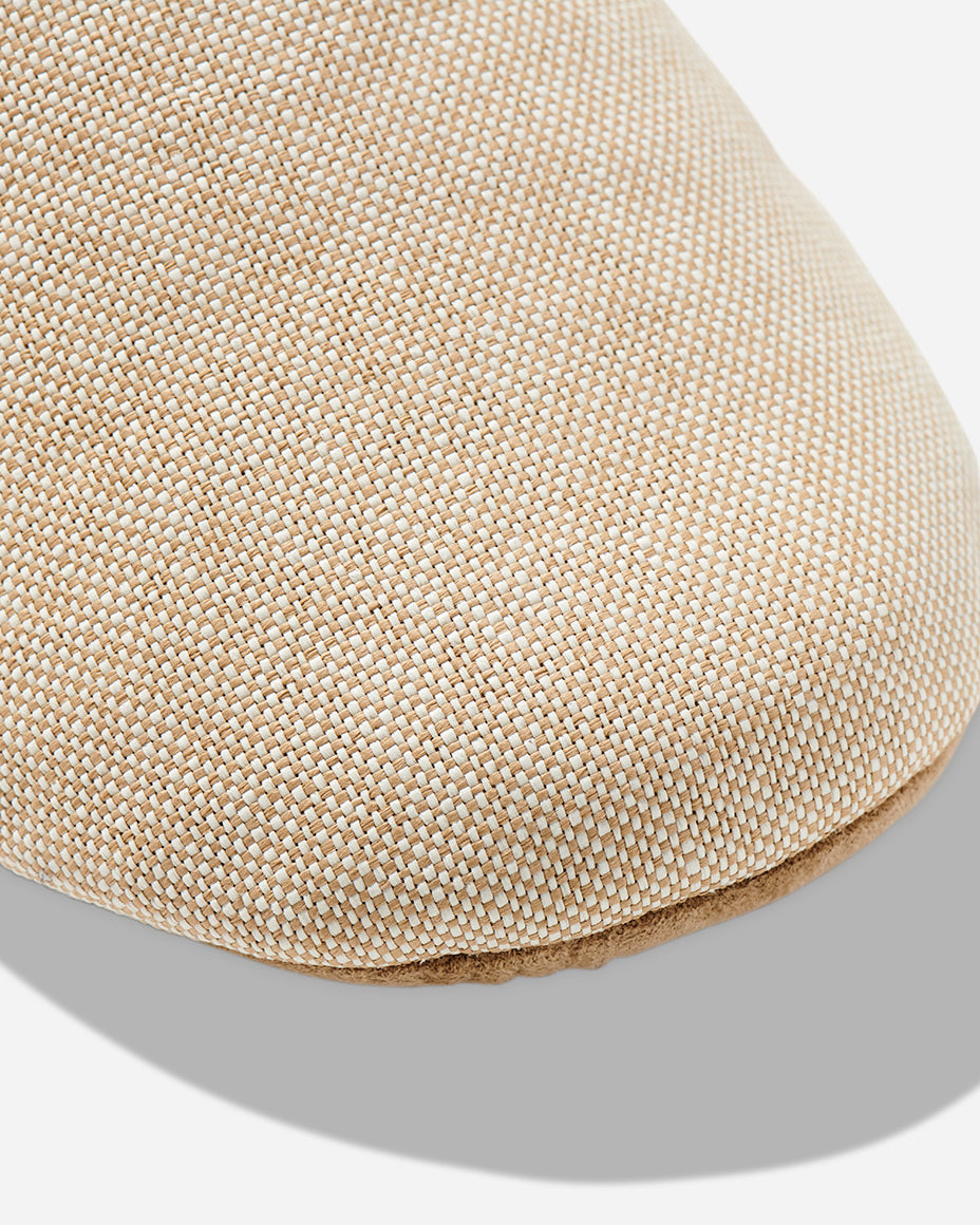 Up-close image of the toe box of a beige color room slipper.