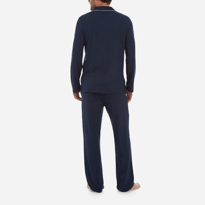A back-facing model is wearing a long pajama set made of navy micro modal fabric.