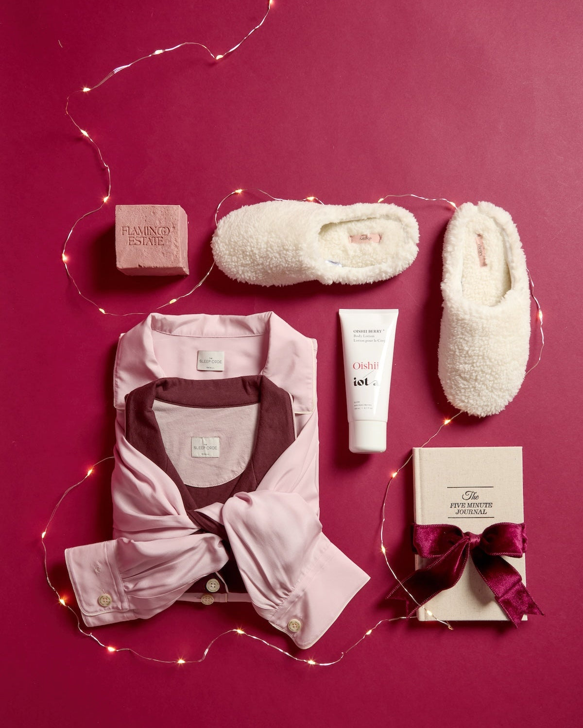 Collection of women's clothing and accessories on a pink background with decorative lights.