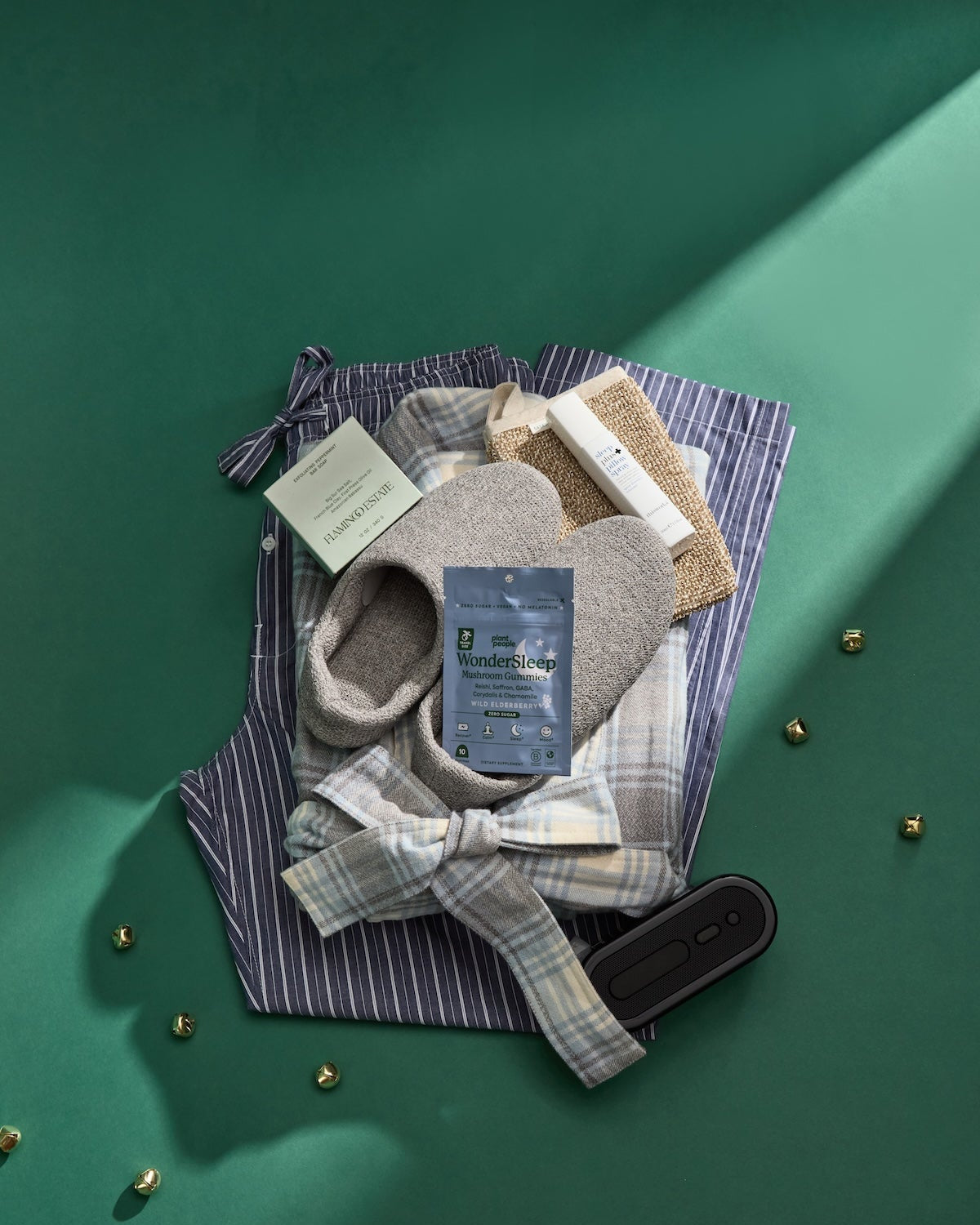 Collection of men's sleep accessories including pajama pants, a bathrobe, and morihata house slippers on a green background