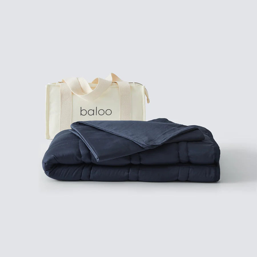 Folded navy blue blanket with a white bag labeled 'baloo' on a light gray background
