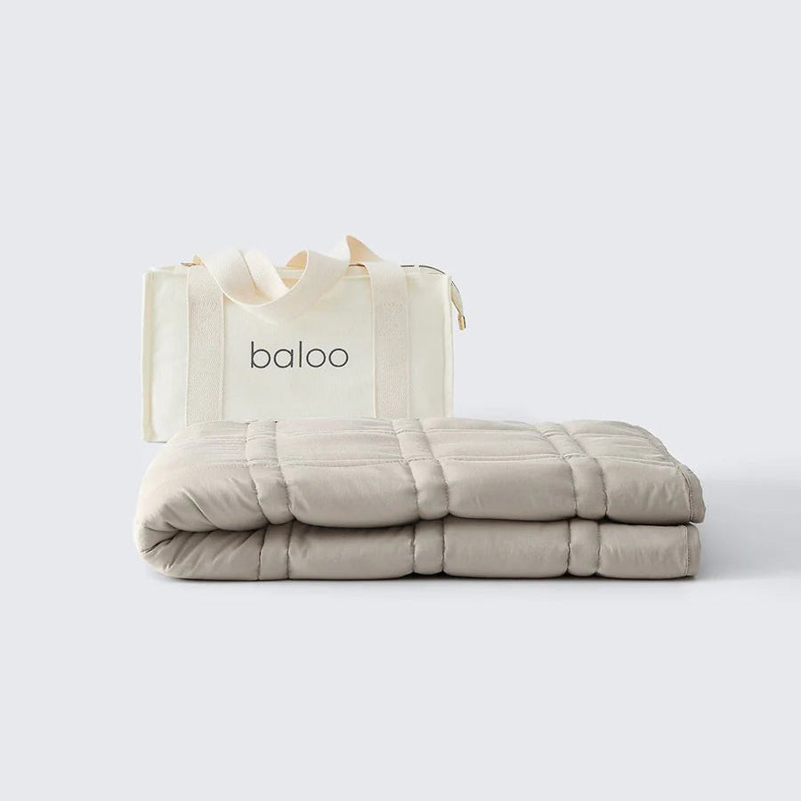 Folded beige blanket with a 'baloo' branded bag on a white background