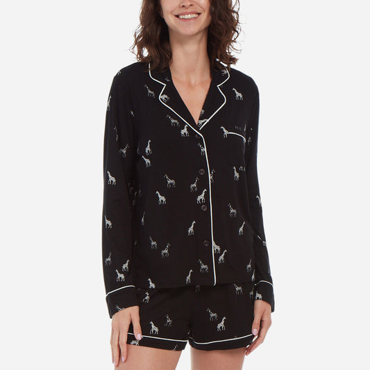 Forward-facing female model is wearing a black long sleeve with shorts pj set. The set has a black and white giraffe print.