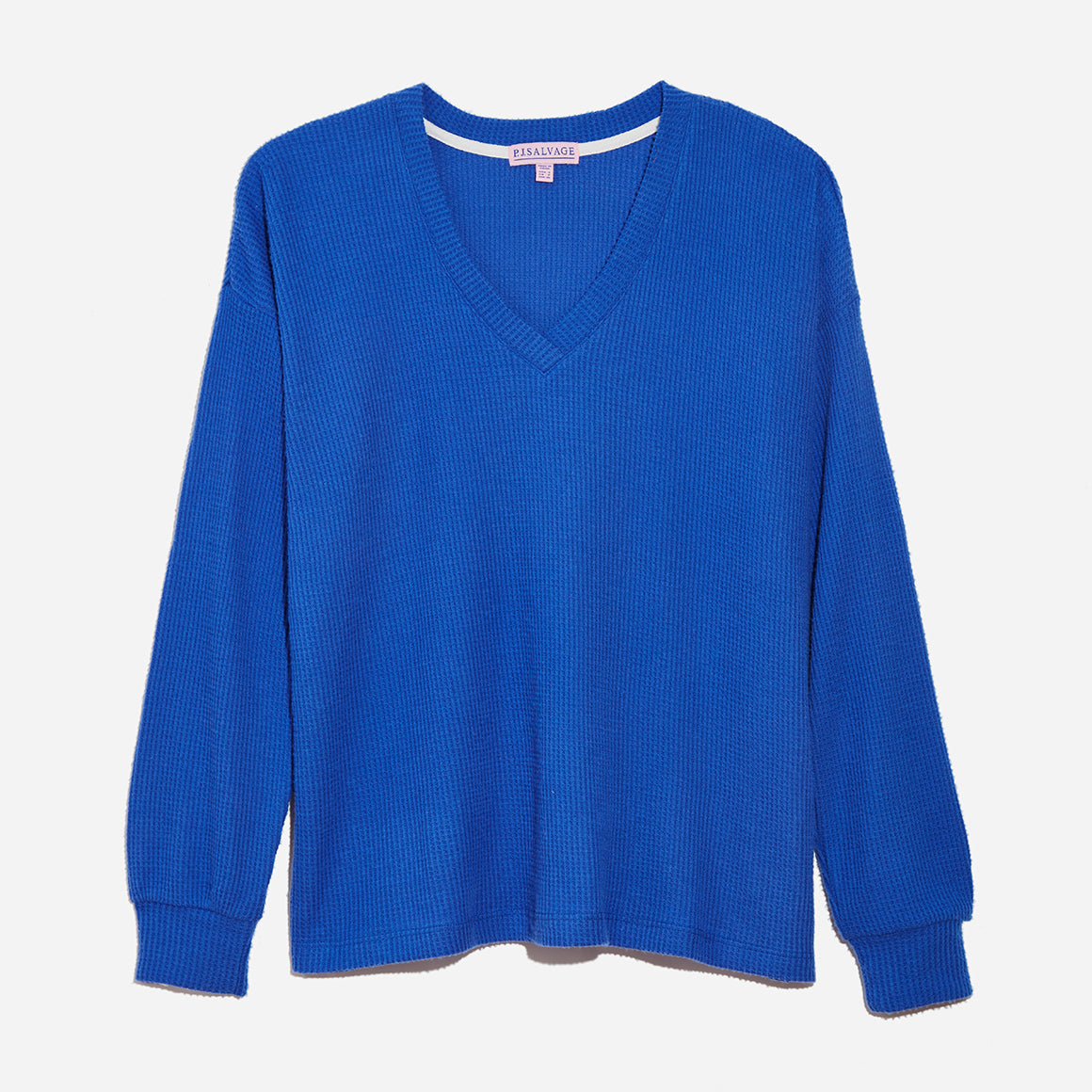 Top-down view of long sleeve waffle knit top in royal blue color. Shot against a grey background.