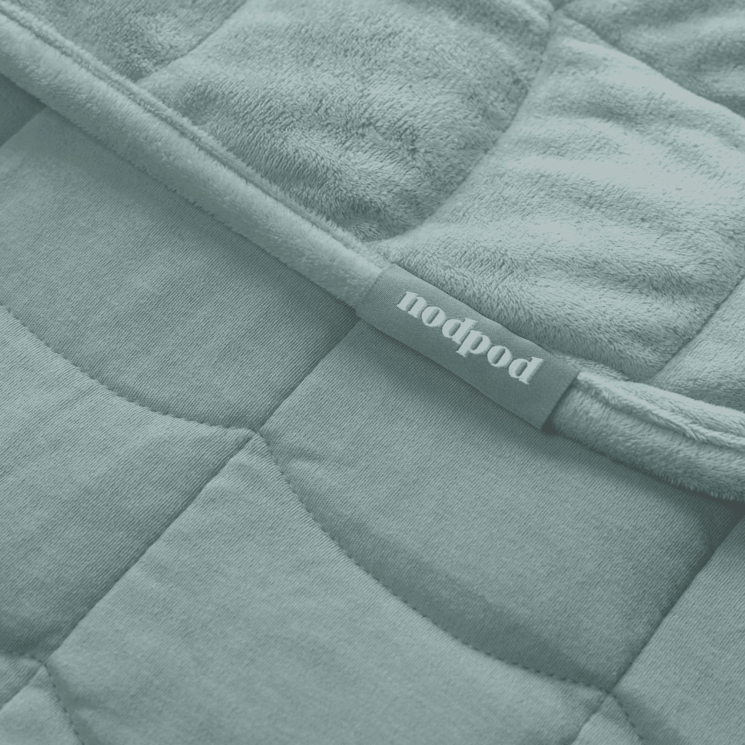 Sage green quilted weighted blanket with 'nodpod' label
