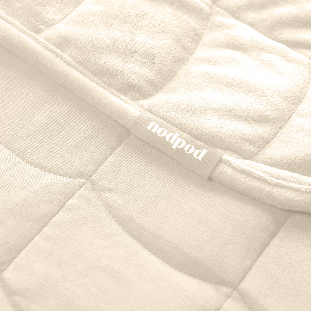 Close-up of a bone quilted weighted blanket with 'nodpod' branding.