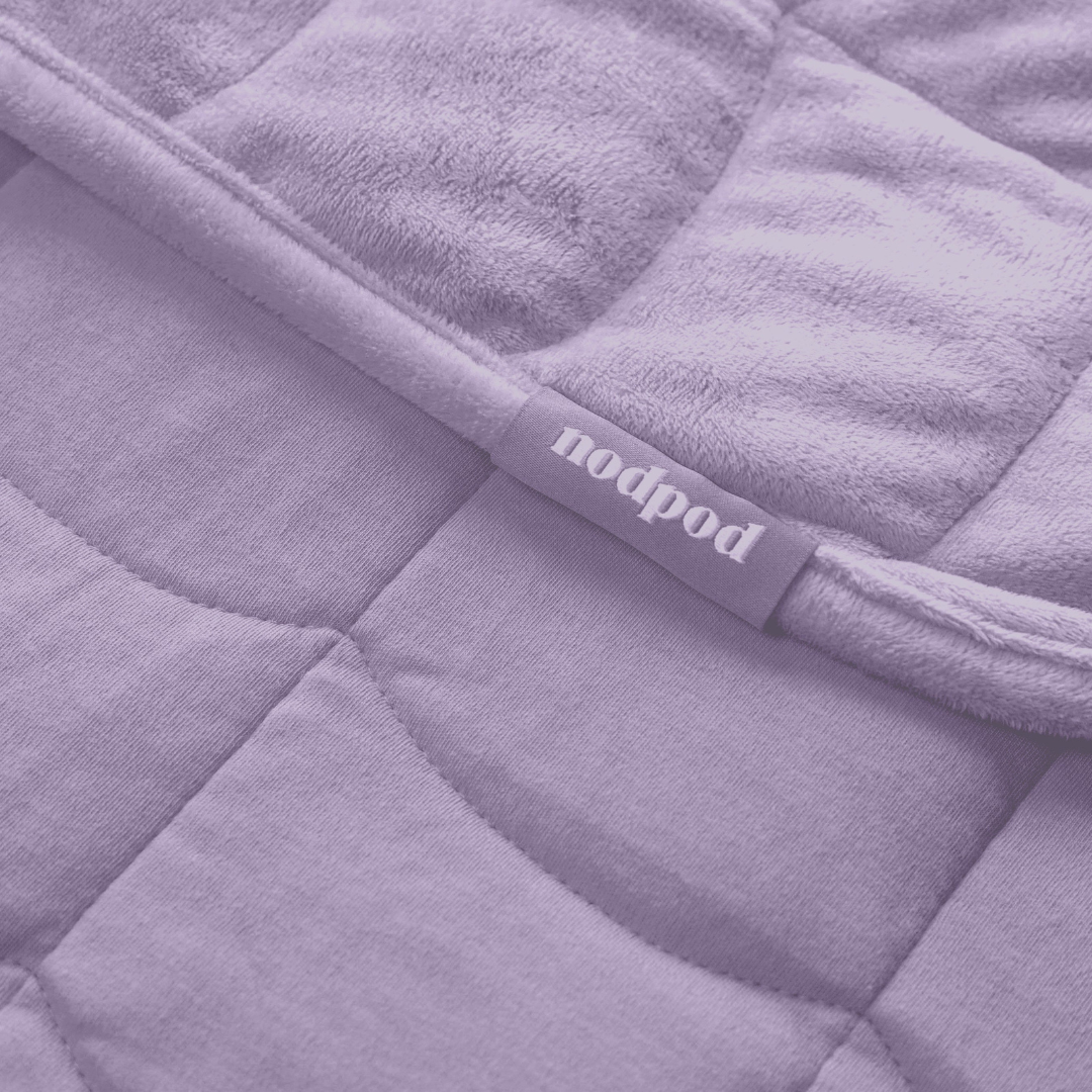 Close-up of a purple quilted weighted blanket with 'nodpod' label