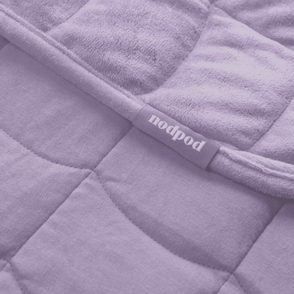Close-up of a purple quilted weighted blanket with 'nodpod' label