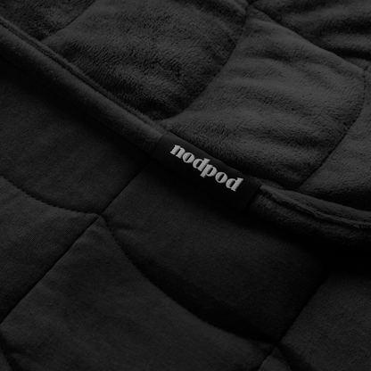 Close up of a black quilted weighted blanket with 'nodpod' label.