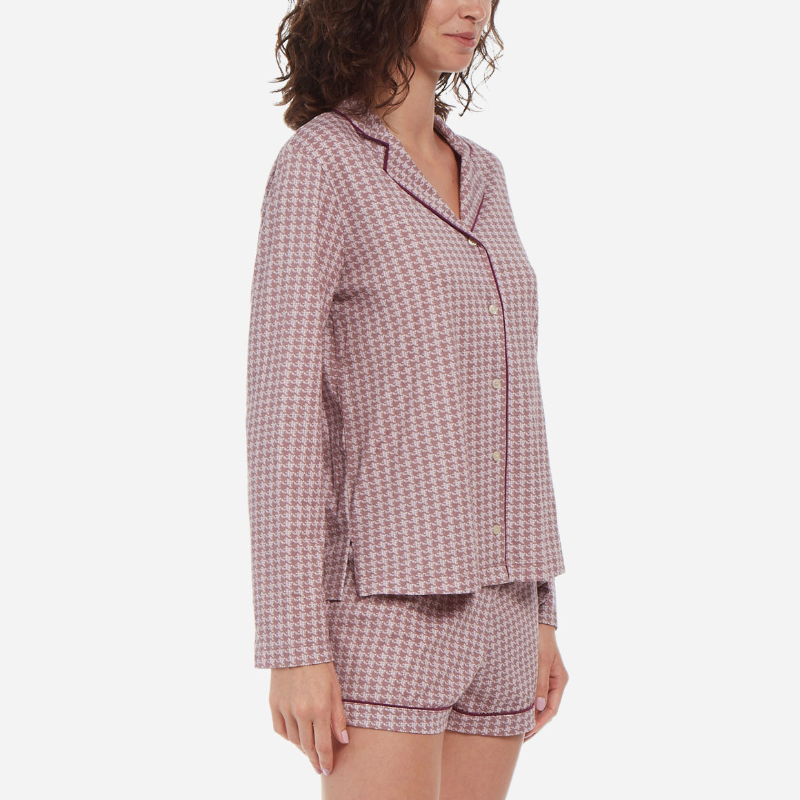 Side facing model wearing a long sleeve button up top and shorts pajama set.