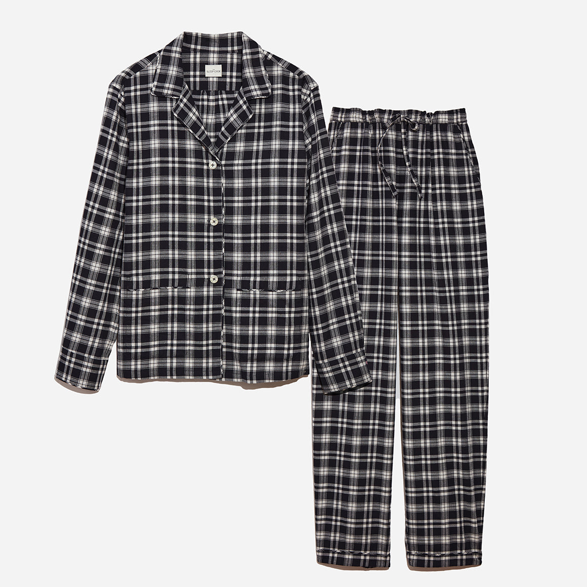 Flat lay image of black and white plaid long sleeve pajamas.