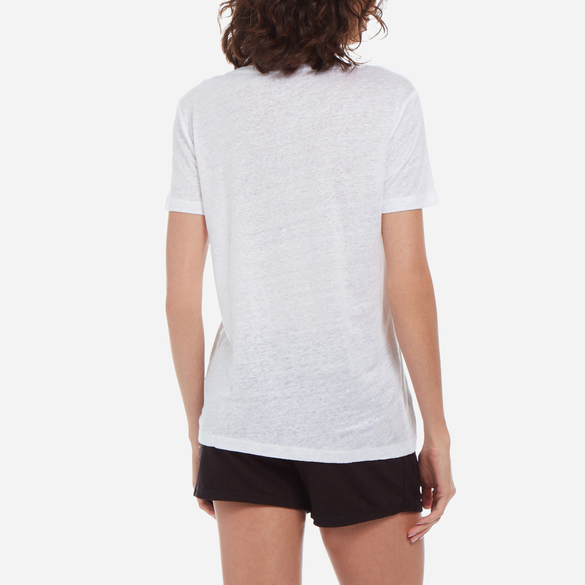 Back-facing model wearing a white linen v-neck tee and black shorts.