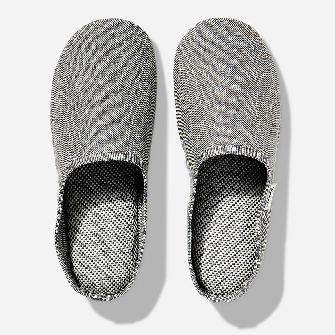 Japanese-style room slippers in light grey color photographed against a white background. Each slipper has Saswashi written on tag near foot opening.