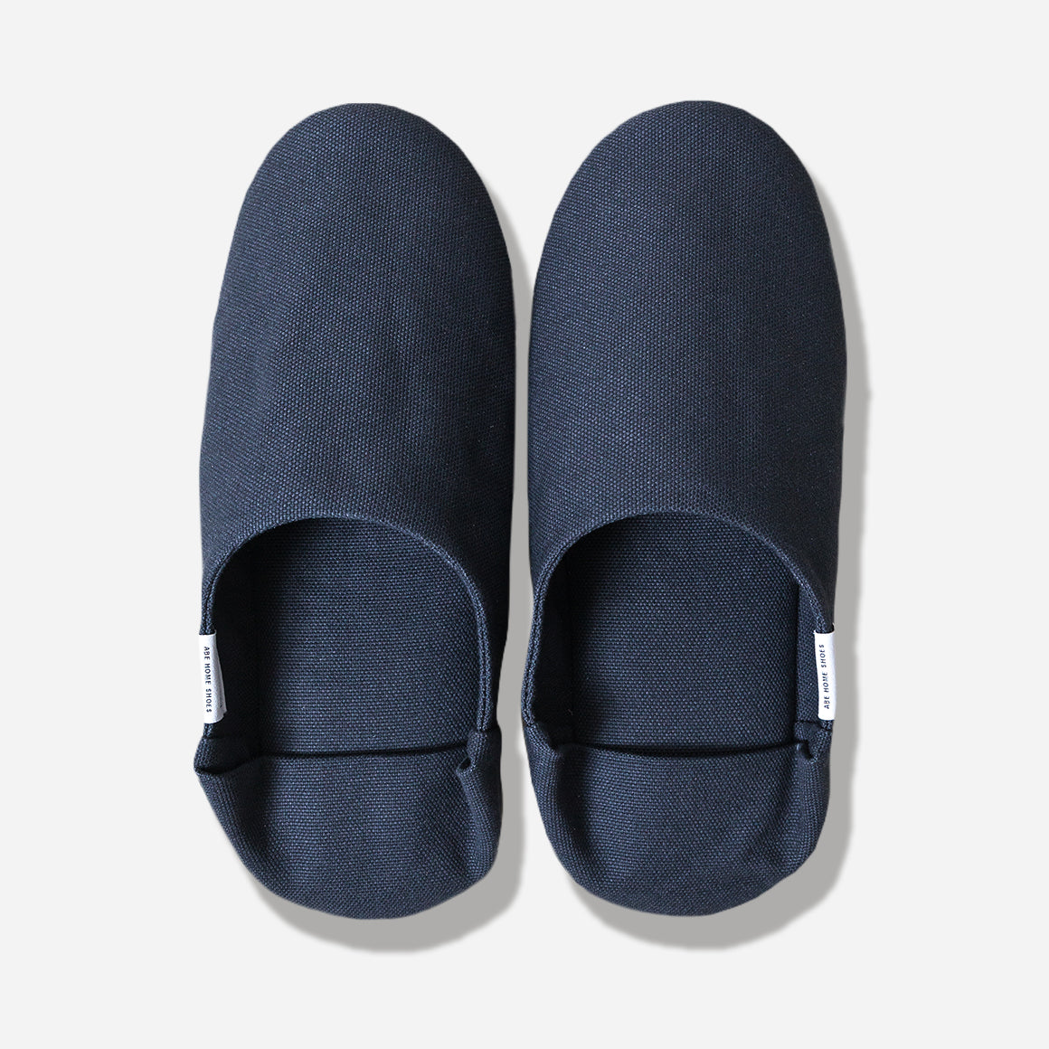Top-down view of navy slippers with heel flap folded down. Shot against a white background.