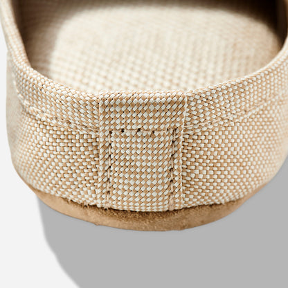 Up-close image of the heel of a beige color room slipper.