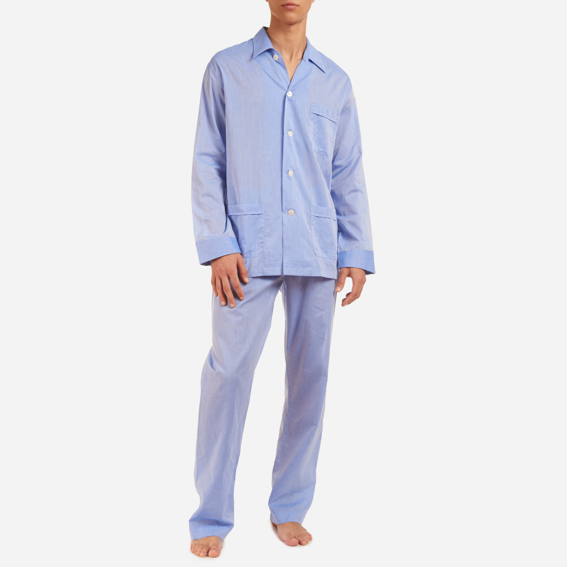 A front-facing model is wearing a long pajama set made of blue cotton batiste fabric.
