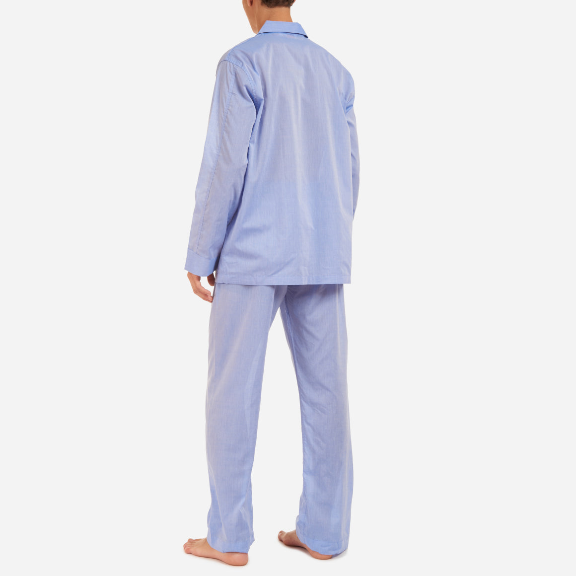 A back-facing model is wearing a long pajama set made of blue cotton batiste fabric.