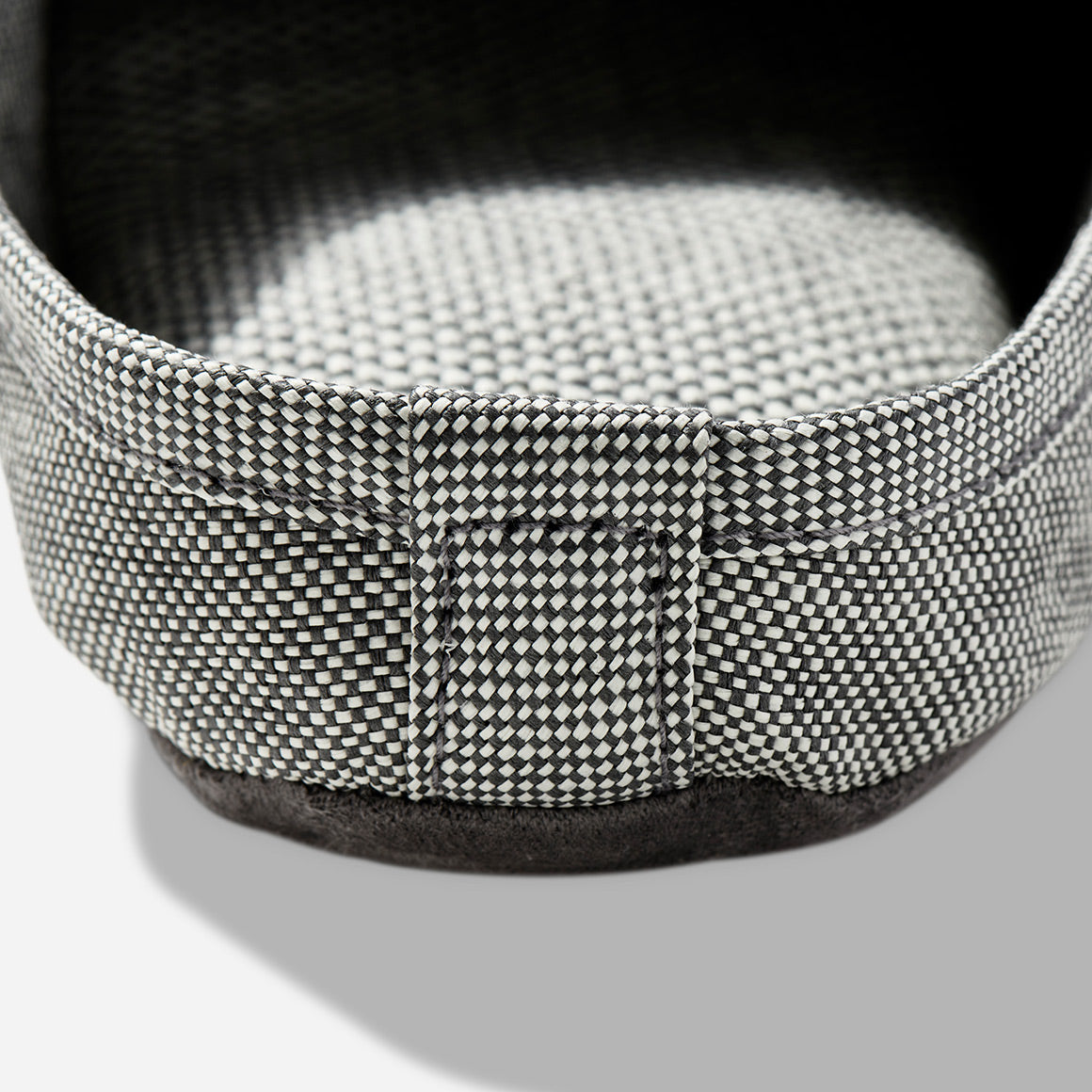 Up-close image of the heel of a light grey room slipper.