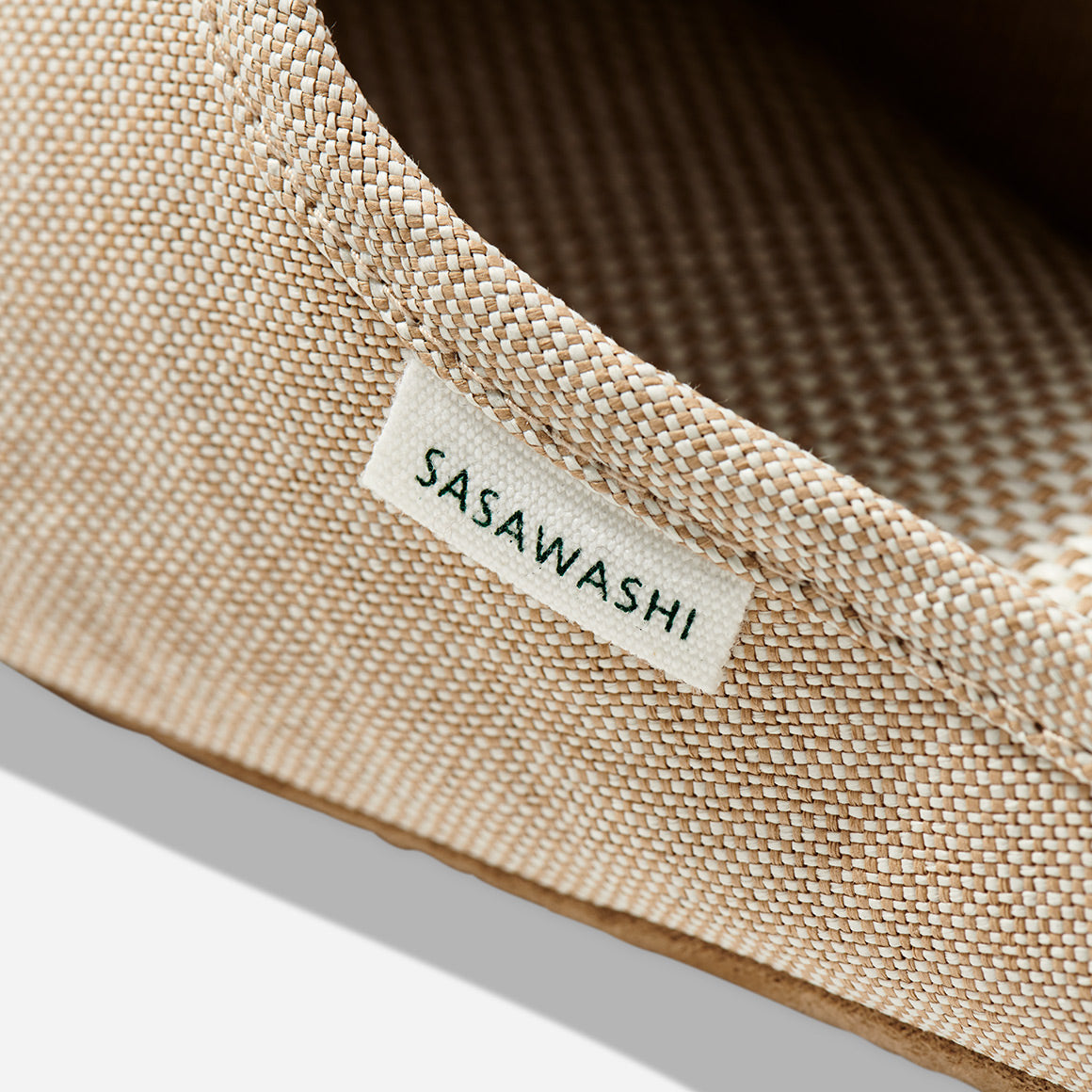 Up-close image of the side of a beige color slipper with Sasawashi written in black on a white tag.