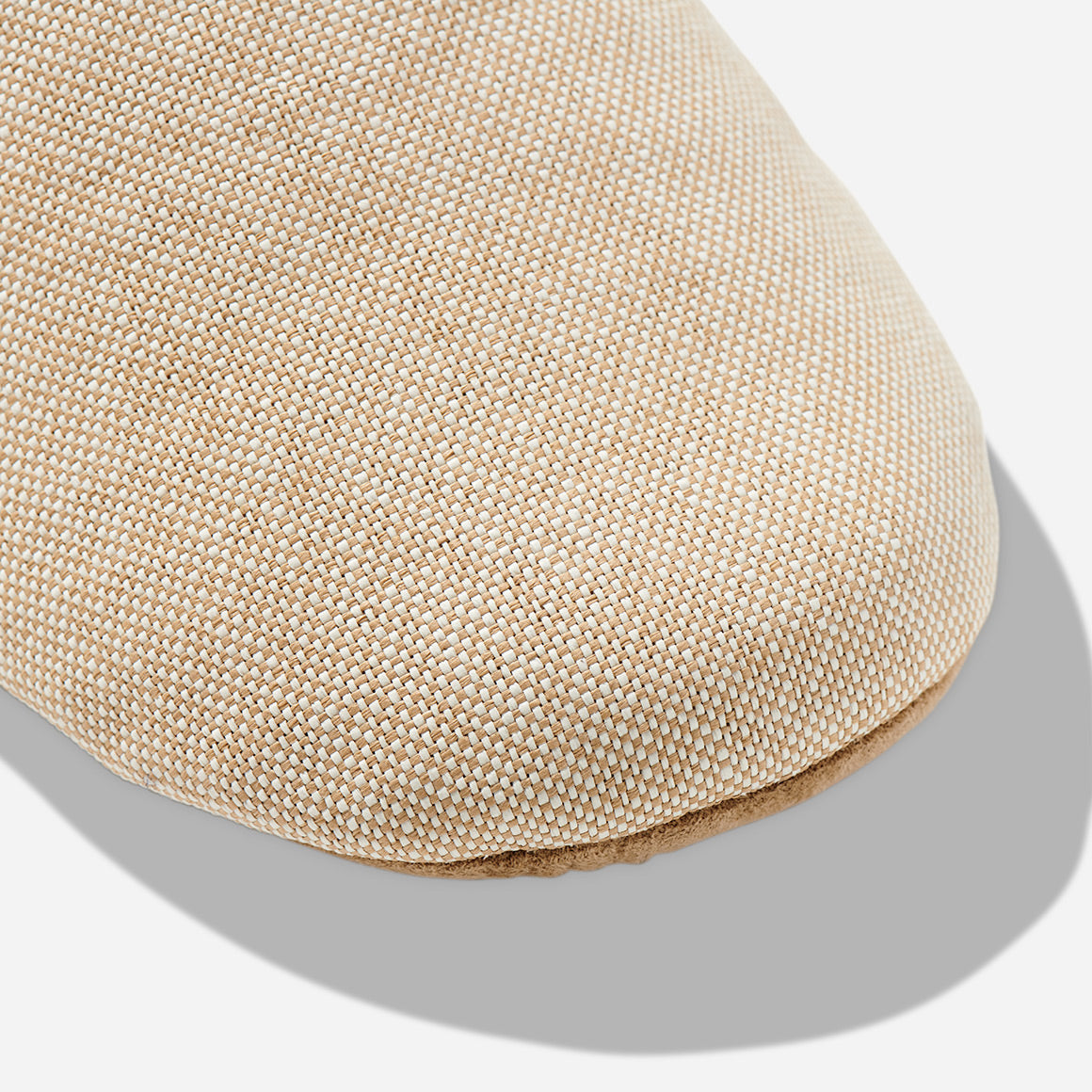Up-close image of the toe box of a beige color room slipper.