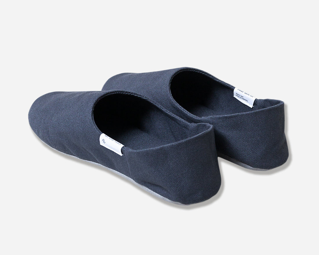 Back view of navy slippers against white background. White label on outside of slippers with Abe Home Shoes written in black.